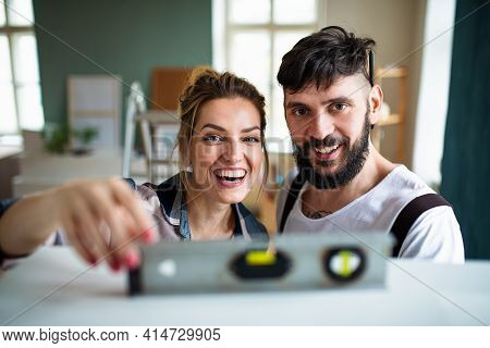 Mid Adults Couple Witj Leveler Indoors At Home, Relocation And Diy Concept.