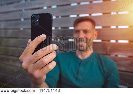 Young Happy Man With Smartphone Outdoors At Sunset. Man Using Modern Black Smartphone. Man Having A 