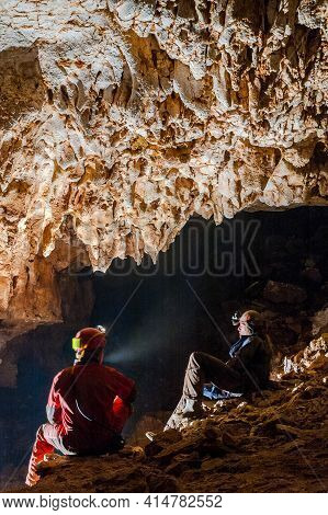 Speleologists Wondering And Admiring Stalactites In A Cave