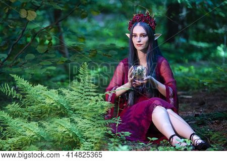 Caucasian Girl With Artistic Elf Ears And Flowery Garland Holding Glass Dome With Grounded Flower Wh