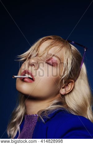 Woman In The Style Of The 70S, 80S, 90S. A Blonde Woman In Bright Glasses And With A Cigarette Sits
