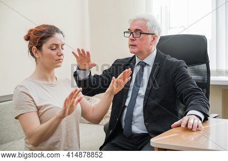 Mature Gray-haired Man Hypnotizes Caucasian Woman During Hypnotherapy Session. The Psychologist Uses