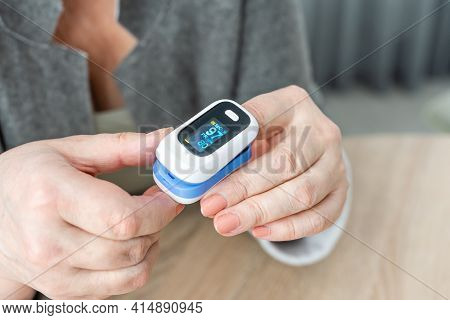 Pulse Oxymeter On A Woman Finger Hand On A Wooden Table. Top View.