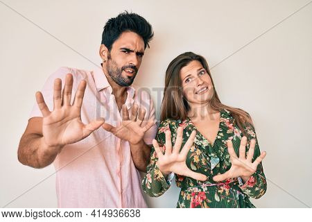 Beautiful young couple of boyfriend and girlfriend together afraid and terrified with fear expression stop gesture with hands, shouting in shock. panic concept. 