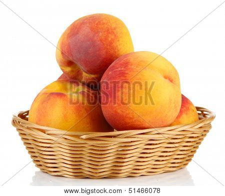 Ripe sweet peaches in wicker basket, isolated on white