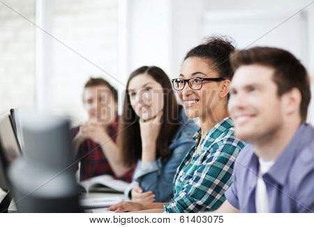 education concept - students with computers studying at school