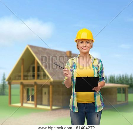 repair, construction and maintenance concept - smiling woman in helmet with clipboard