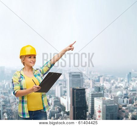 repair, construction and maintenance concept - smiling woman in helmet with clipboard pointing finger