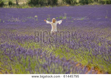 Beautiful little girl runs and jumps in the middle of a field of lavender