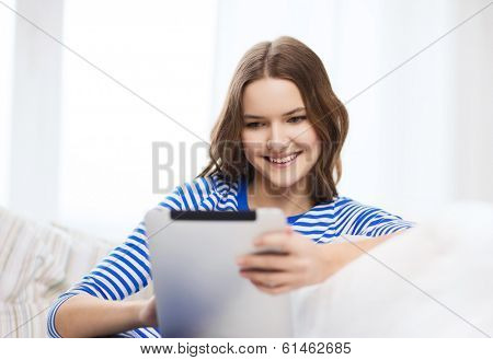 home, technology and internet concept - smiling teenge girl lying on the couch with tablet pc computer at home