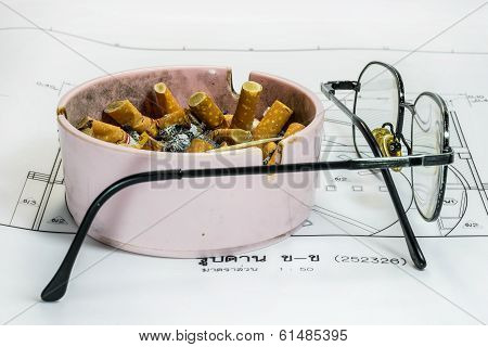Ashtray And Glasses On White Blueprint Background.