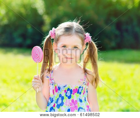 Adorable Little Girl With Two Blond Ponytails Holding White And Pink Lollipop In Her Hand, Outdoor S