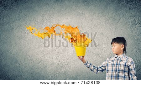 Young boy splashing colorful paint from bucket