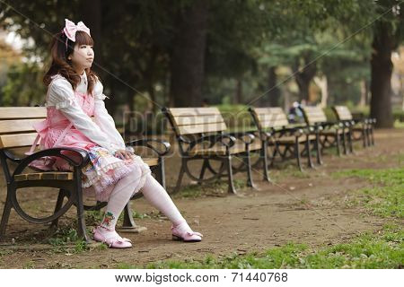 Japanese girl in lolita cosplay fashion sitting on a bench, Tokyo