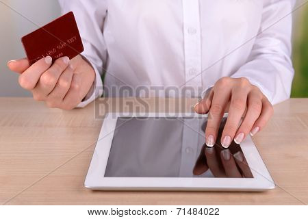 Female hands holding credit card and computer tablet on table on close up