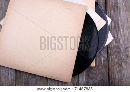 Vinyl records records and paper covers on wooden background