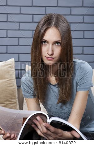Mladý dospělý sedí na pohovce a číst časopis