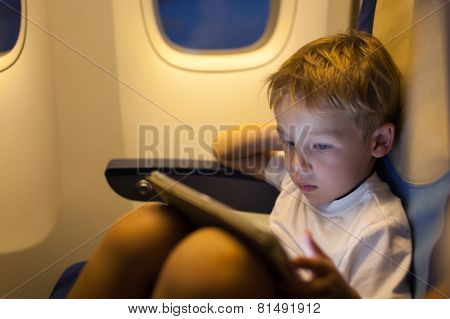 Boy sitting in the plane and using tablet PC