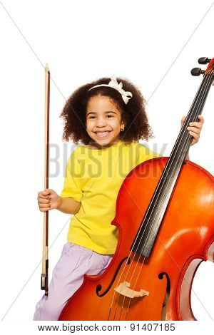 Cheerful African girl holds cello with fiddlestick