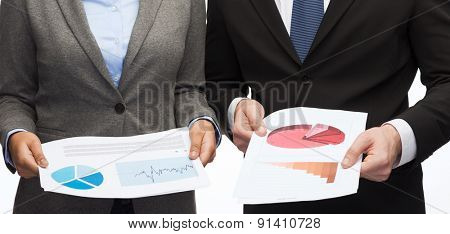 business and economy concept - smiling businesswoman and businessman with graphs and charts