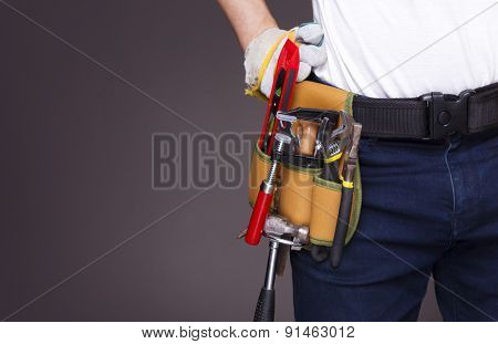 Worker with toolbelt and against dark background
