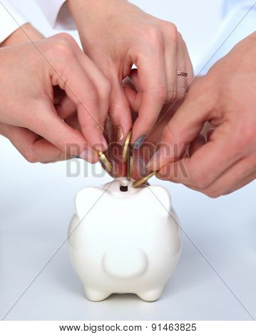 Putting coin into the piggy bank, isolated.