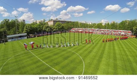 RUSSIA, BOGORODSKOE - MAY 14, 2014: Teams walk by soccer field with country flags during international competition at Spartakovec stadium named by N.P. Starostin. Aerial view