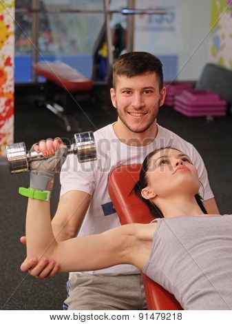 Young fitness coach stands by the girl drill