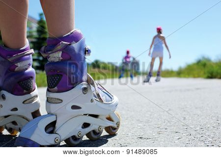 Children Ride On Roller Skates In The Park On A Warm Summer Day