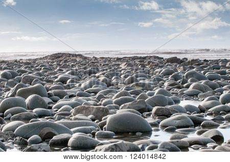 Pebbles at the beach in the foreground of a coastal scene