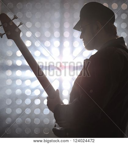 Bassist playing bass guitar in smoke. backlight