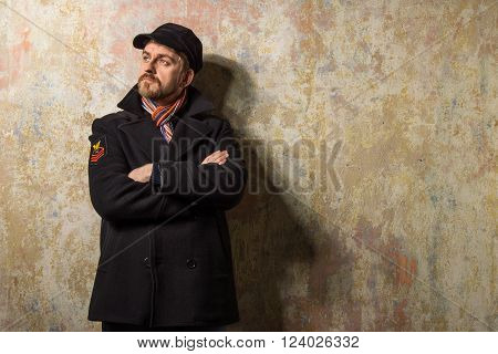 image of a caucasian man with grungy blond hair dressed warmly in a stylish black trench coat and a funky hat and scarf for the cold winter