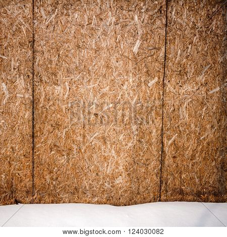 Old weathered plywood fence and a ground covered with snow