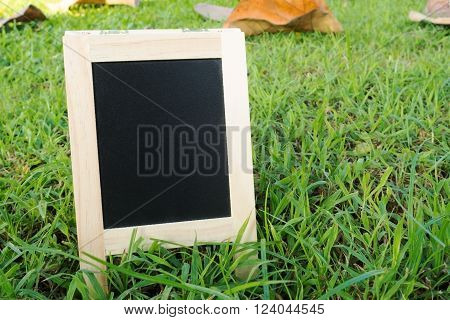 Small wood A-frame blackboard with blank area for text on fresh green grass field. Wooden black board with blank area for message.