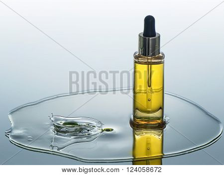 The bottle of  moisturizing cosmetic oil stands on the water background with splash near the bottle