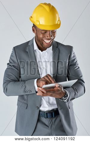 Candid smiling portrait of african architect engineer designer with touchscreen tablet device in business suit isolated in studio