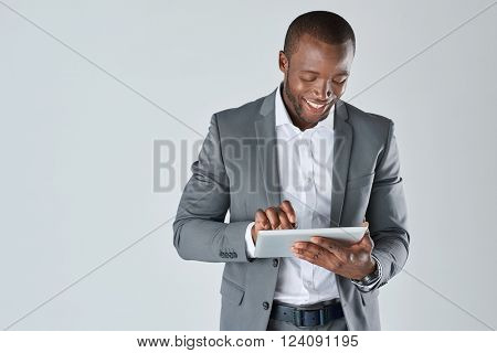 Candid portrait of positive friendly black  professional businessman with touchscreen tablet device isolated in studio