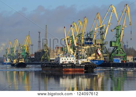 ST. PETERSBURG, RUSSIA - FEBRUARY 17, 2016: Cargo cranes move loads in ships in port. A sunny february day at Kanonersky channel