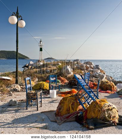 Multicolored fishing nets and blue chairs on the pier street lantern and small lighthouse next to the sea Skopelos island; Sporades; Greece