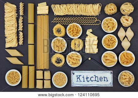 Dried italian pasta food collection with kitchen sign forming an abstract background over grey.