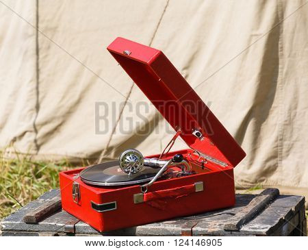 old red portable gramophone on background army tent