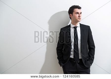 Businessman in smart suit hands in pockets. White background shade. Concept of business fashion.