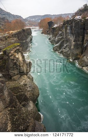 Image of river with green waters, snow and ice near Meteora in Greece