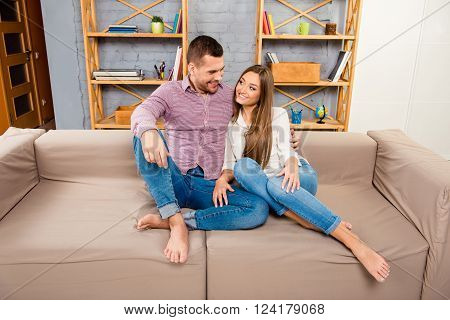 Young Couple In Love Sitting On The Sofa And Looking On Each Other