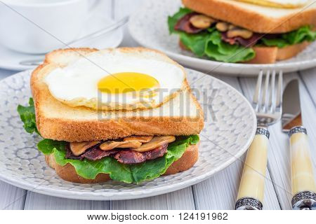 Traditional french toasted sandwich Croque madame with bacon and mushrooms