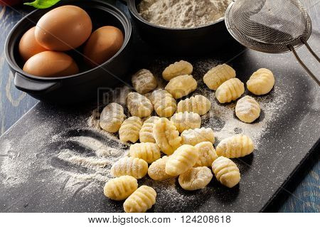 Uncooked homemade gnocchi on black cutting board