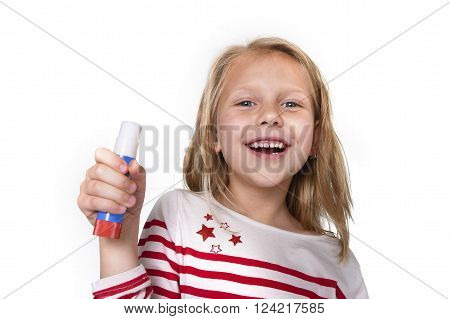 sweet beautiful female child 6 to 8 years old with cute blonde hair and blue eyes holding glue stick isolated on white background in education and primary or junior school supplies concept
