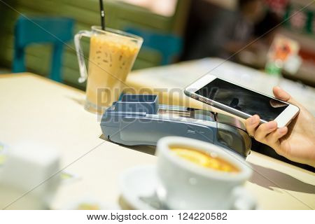 Woman using mobile phone to pay the biil with NFC technology