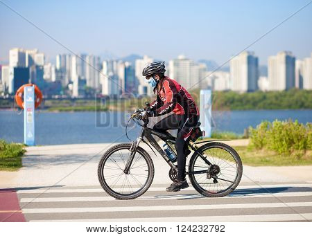 SEOUL KOREA - APRIL 24 2015: A man cycling at a racreation park zone on the bank of Hangang river in Seoul Korea