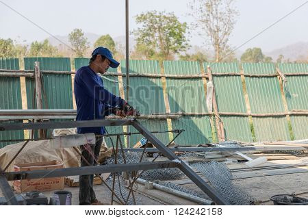 Petchaburi, Thailand - February 20, 2016: One man worker cut iron frame for making fence at prepared area for construction on February 20, 2016 in Petchaburi, Thailand